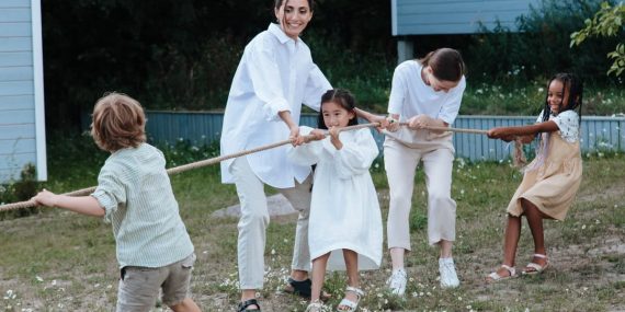 Family playing tug of war in backyard, showcasing teamwork and joy.